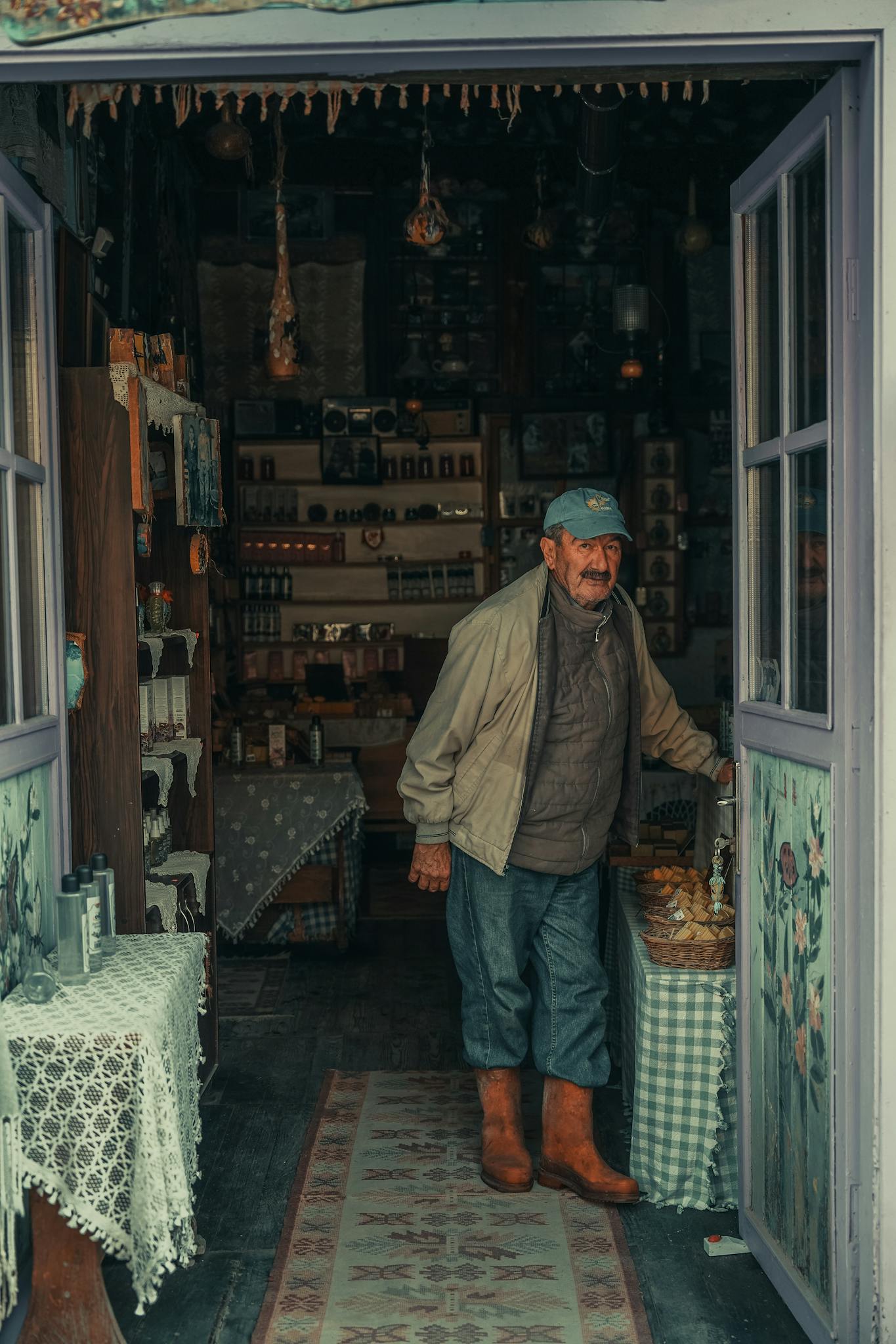 Elderly man wearing a cap stepping out of a cozy, rustic store adorned with vintage decor.